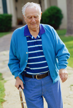 Man walking outdoors with cane.